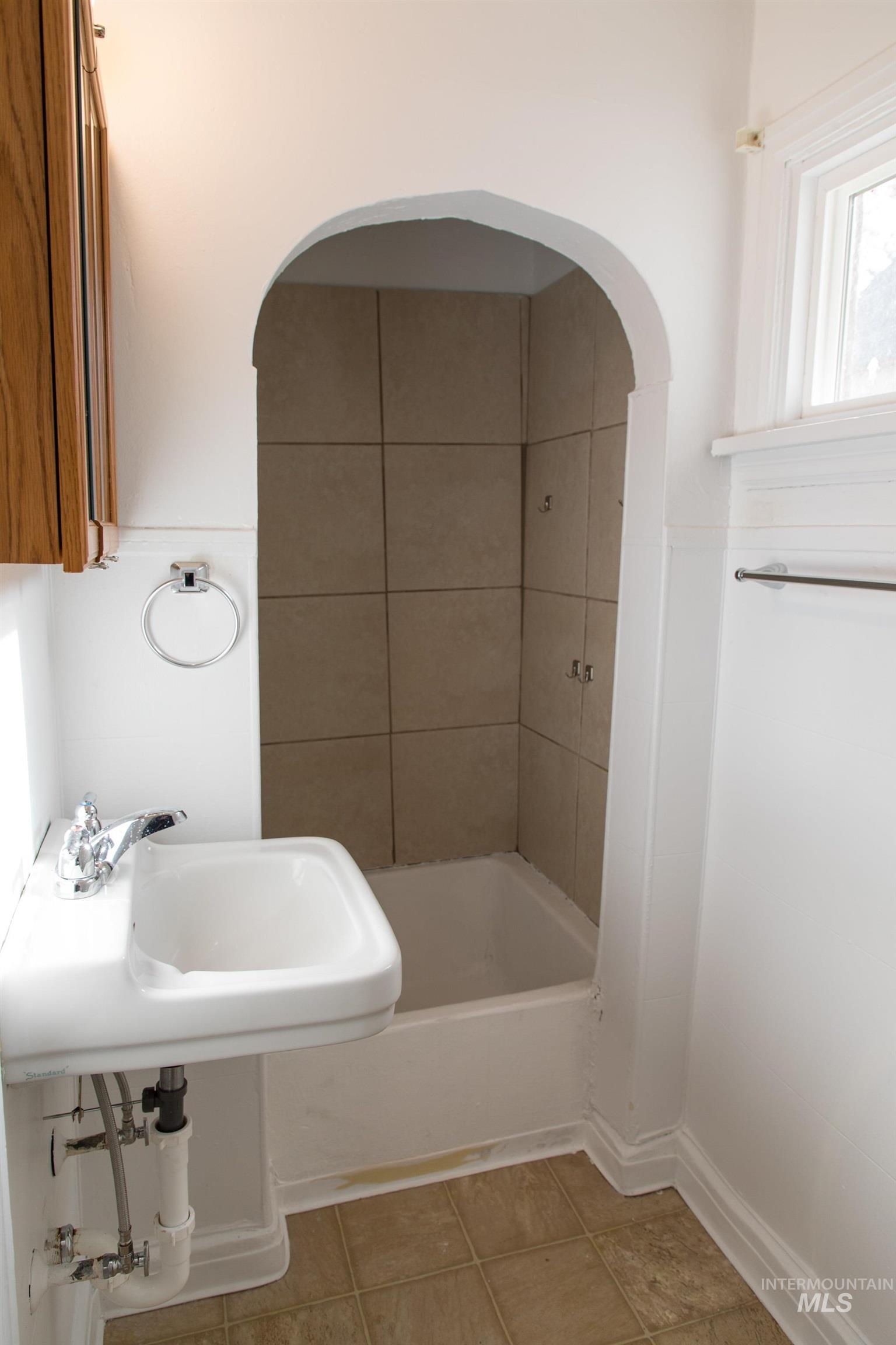 Full bathroom featuring light tile patterned floors and a sink