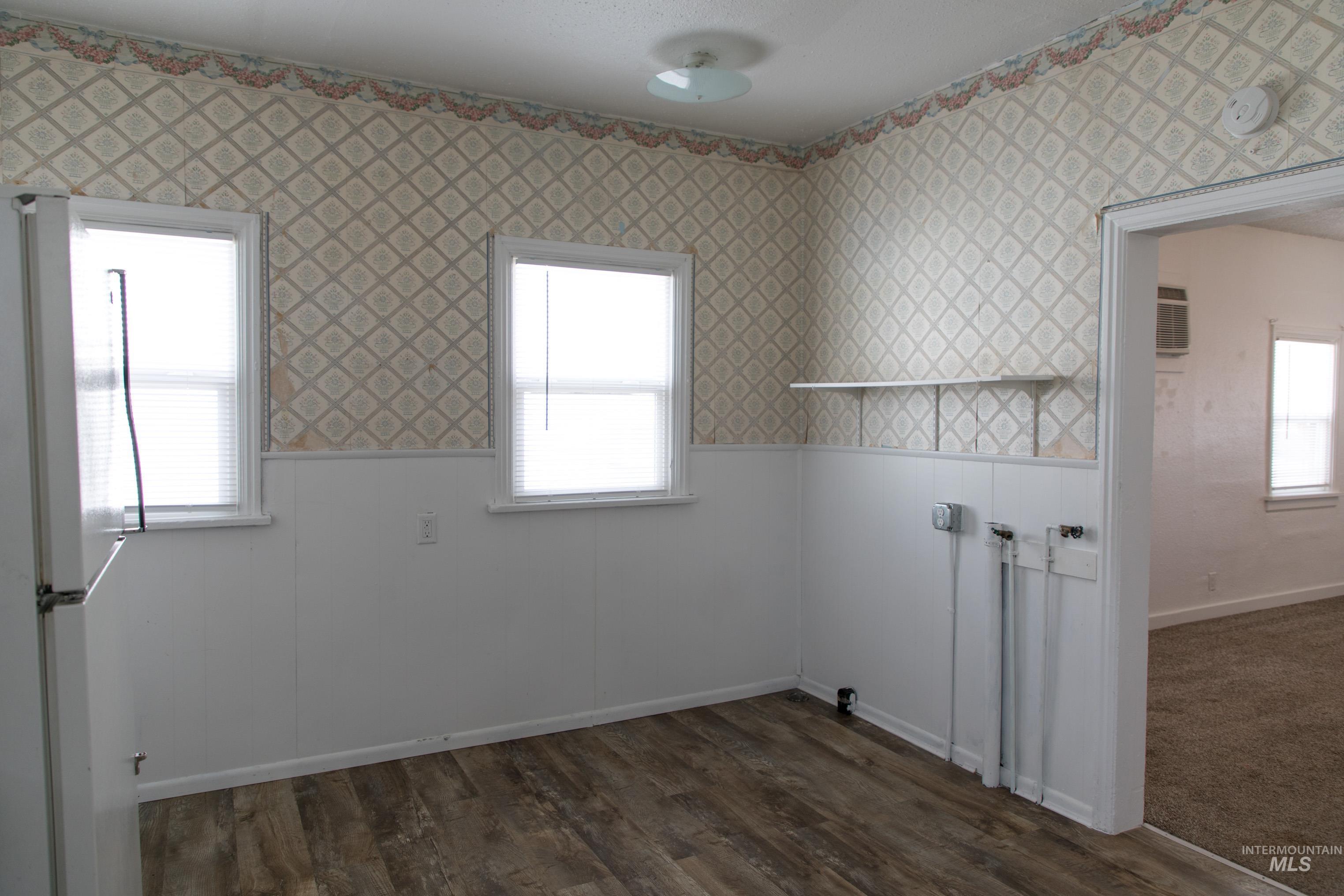 Washroom featuring dark wood finished floors, a wainscoted wall, and wallpapered walls