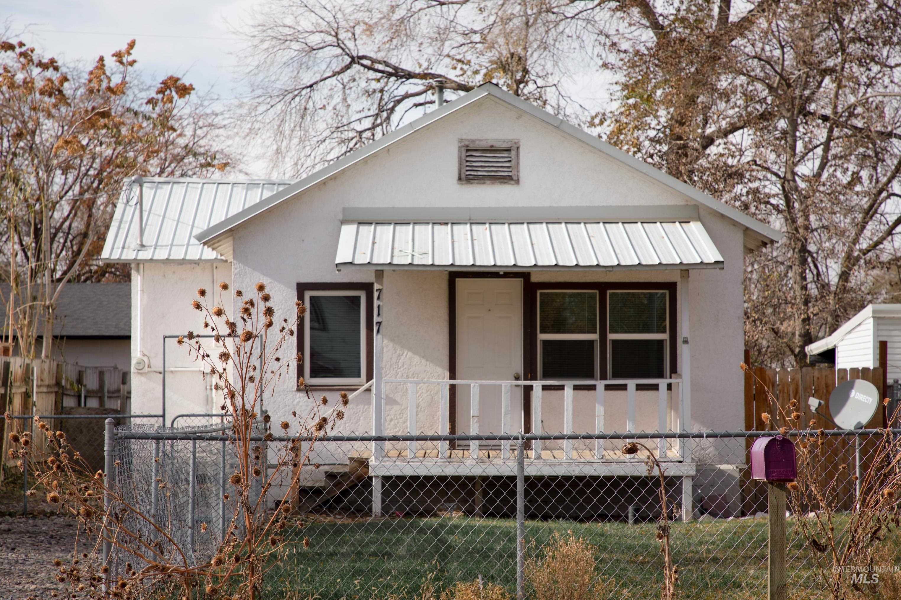 Bungalow with stucco siding, a wooden deck, and a metal roof