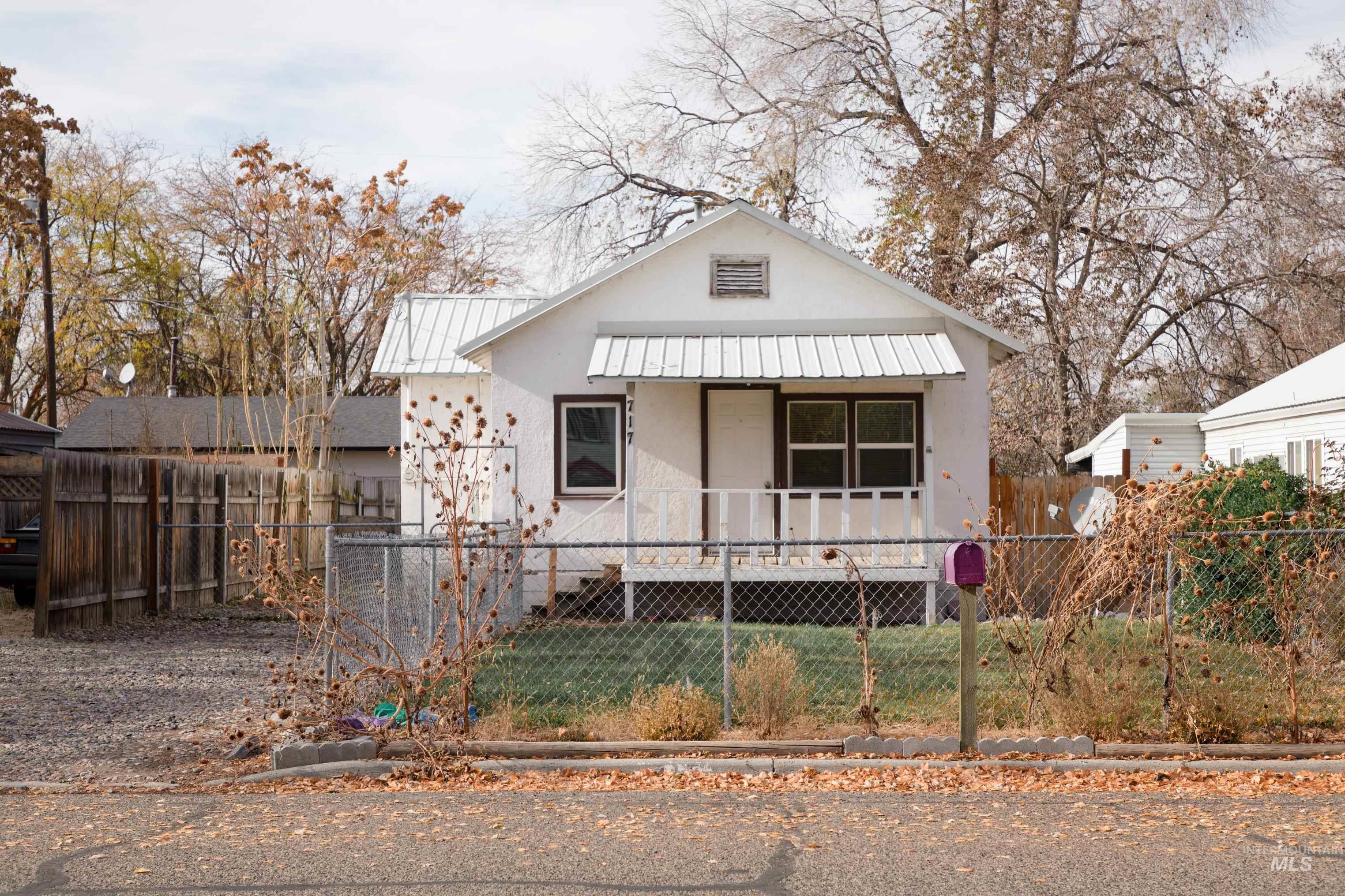 Bungalow featuring a fenced front yard, a metal roof, stucco siding, and a porch