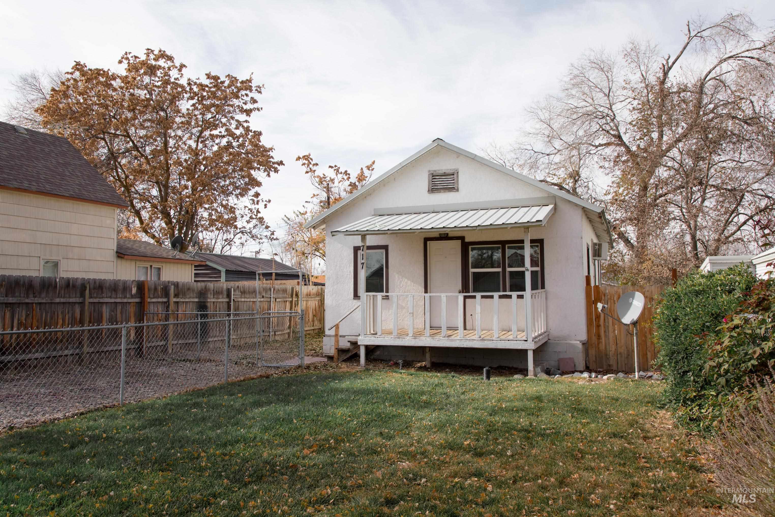 Rear view of house with a fenced backyard, a wooden deck, stucco siding, and a metal roof