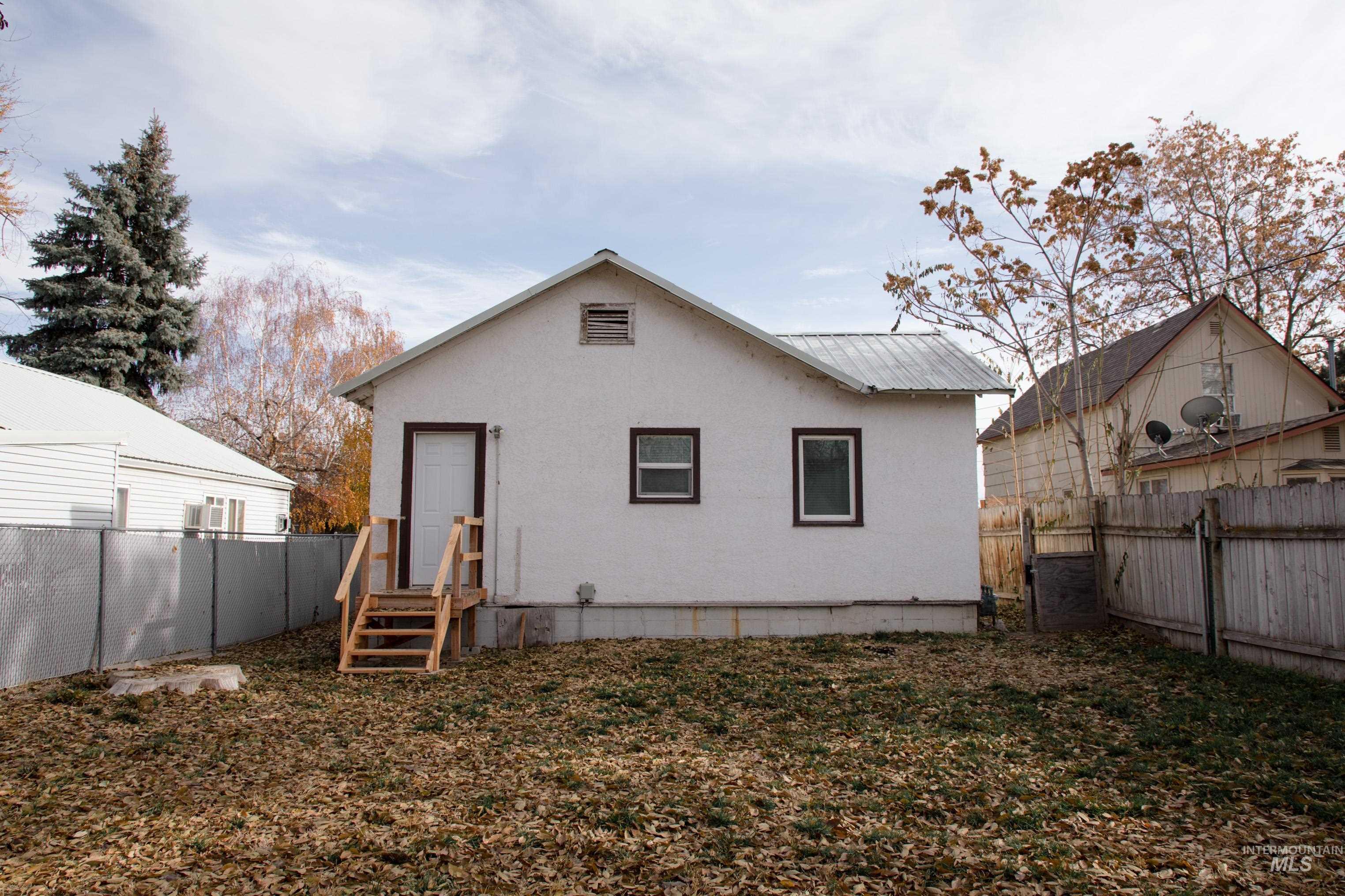 Back of house featuring a fenced backyard, a metal roof, and stucco siding