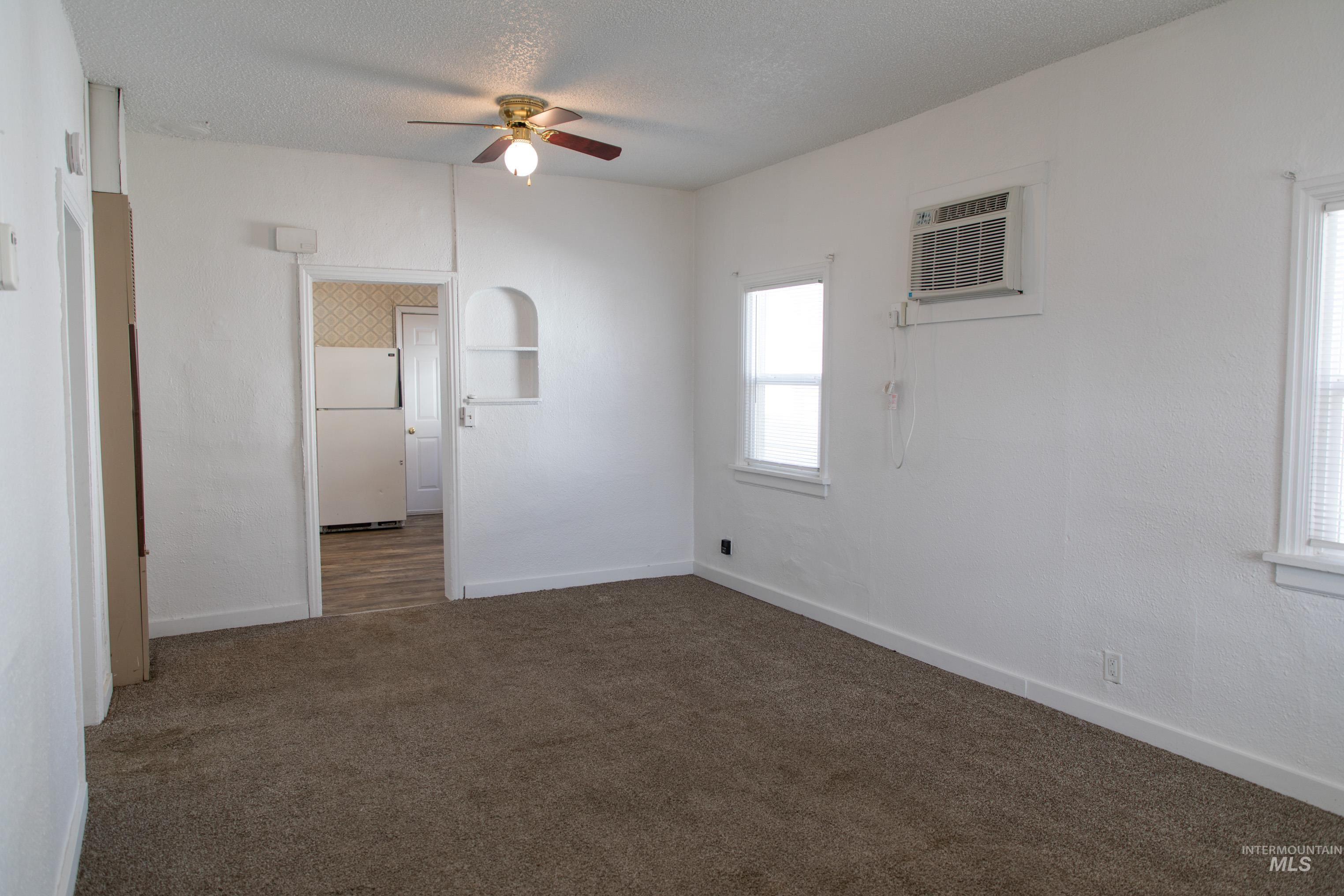 Spare room with dark colored carpet, ceiling fan, a textured ceiling, and a wall mounted AC