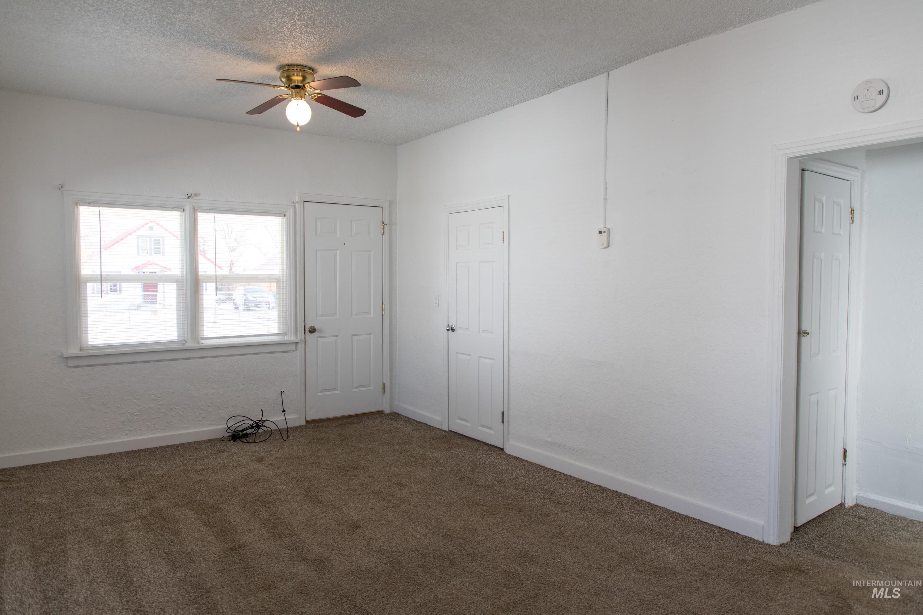 Unfurnished bedroom featuring dark colored carpet, a textured ceiling, and ceiling fan