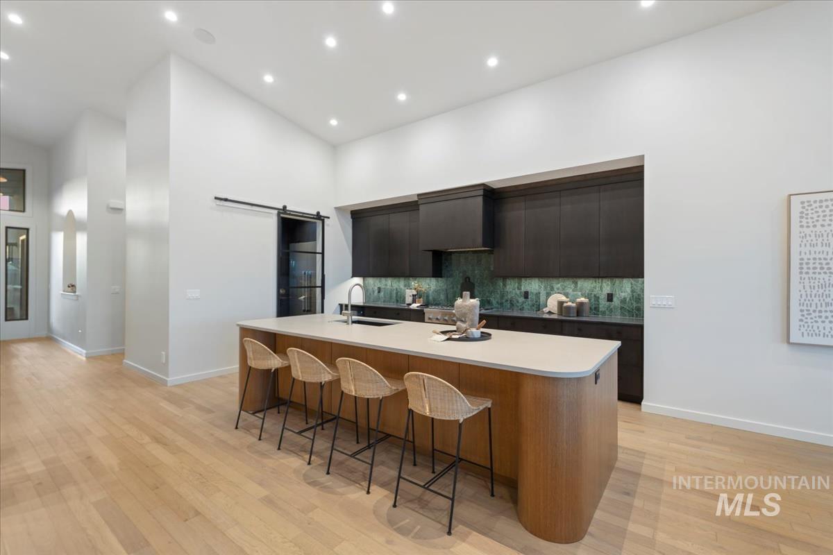 Kitchen featuring a barn door, modern cabinets, a breakfast bar, a large island with sink, and recessed lighting