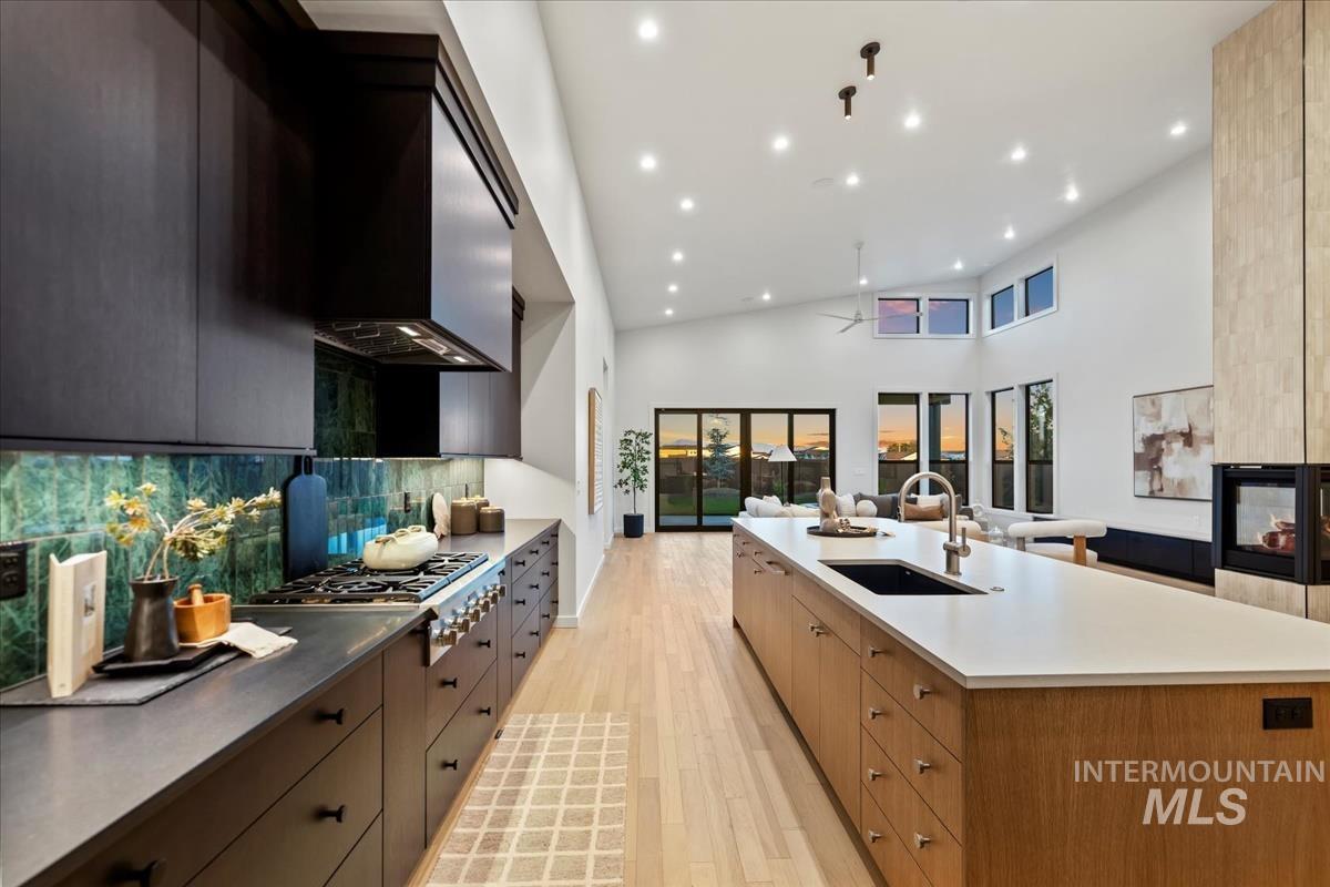 Kitchen featuring open floor plan, modern cabinets, recessed lighting, light wood finished floors, and a multi sided fireplace