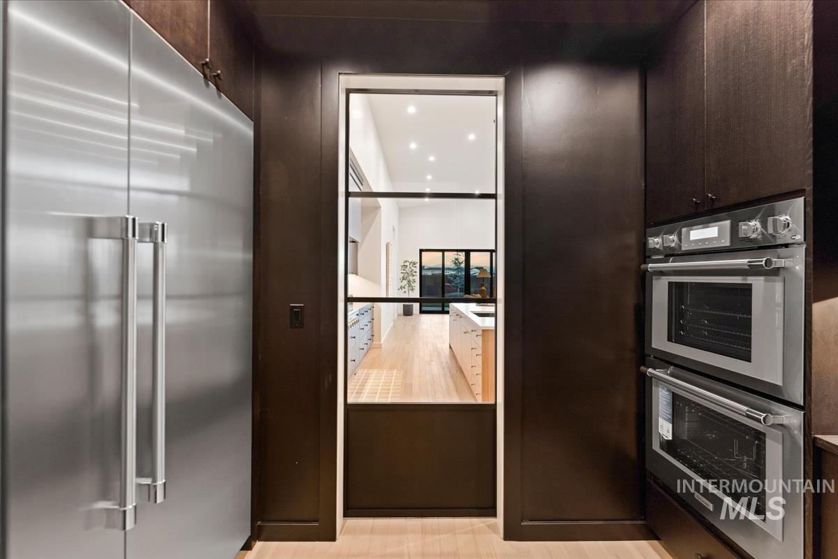 Kitchen featuring side by side stainless steel refrigerator, dark cabinets, and recessed lighting
