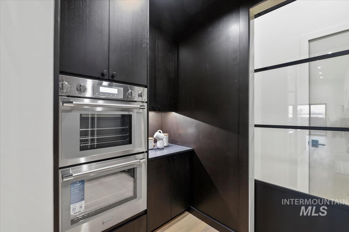 Kitchen with stainless steel double oven, dark cabinetry, and modern cabinets