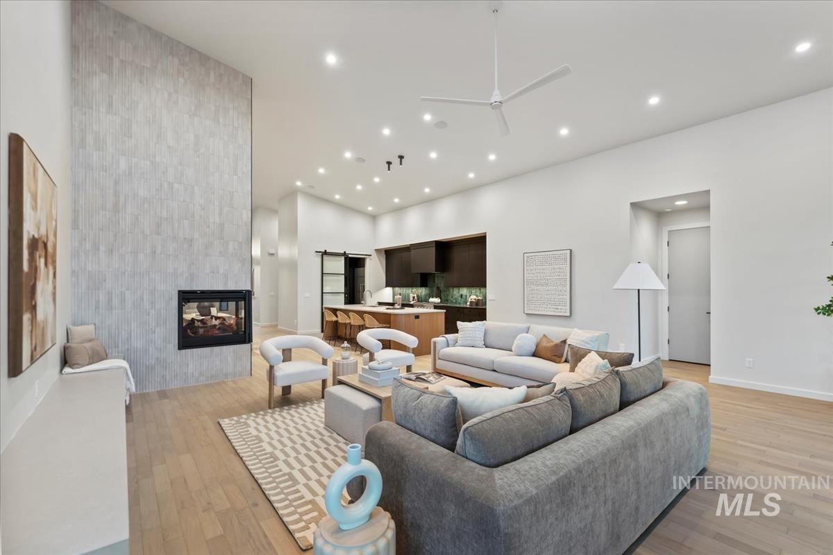Living area with ceiling fan, a tile fireplace, recessed lighting, and light wood-style floors