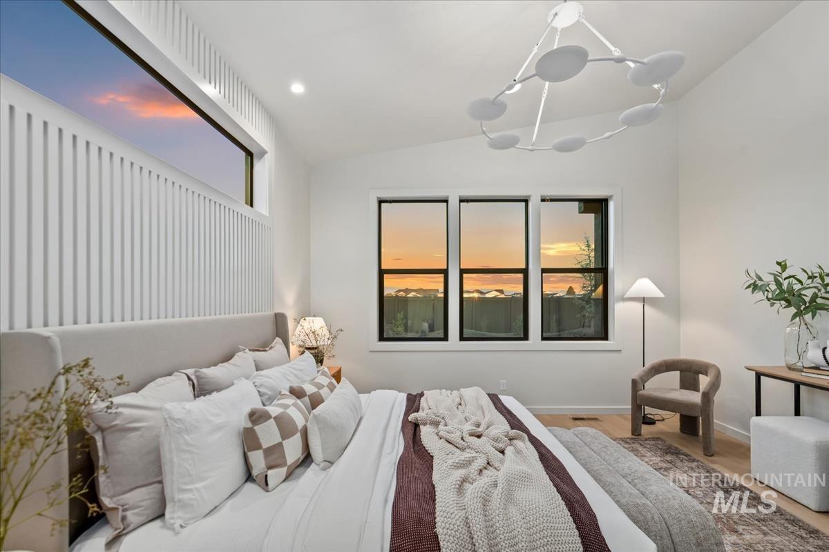 Bedroom with lofted ceiling, a chandelier, wood finished floors, and recessed lighting