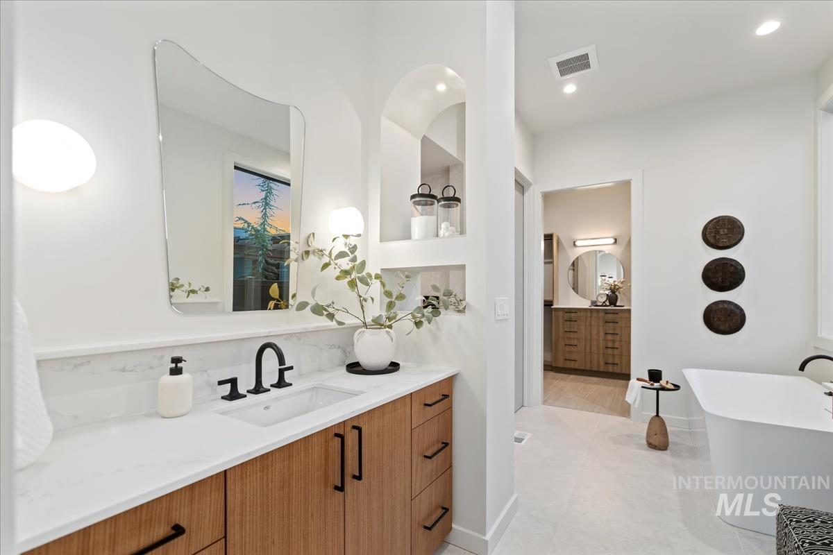 Bathroom with two vanities, a soaking tub, light tile patterned flooring, and recessed lighting
