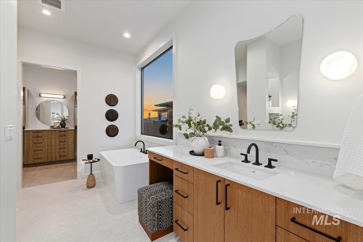 Full bath featuring two vanities, a soaking tub, and recessed lighting