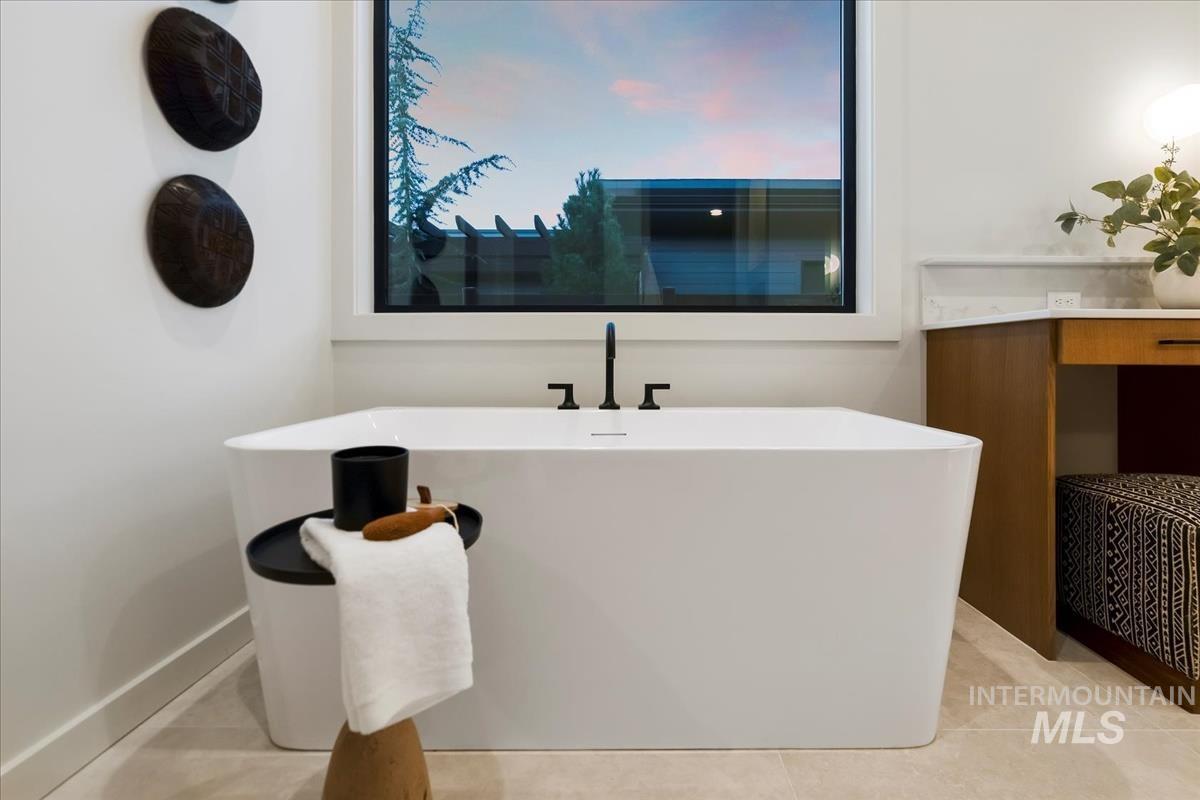 Full bathroom with a freestanding bath, light tile patterned floors, and vanity