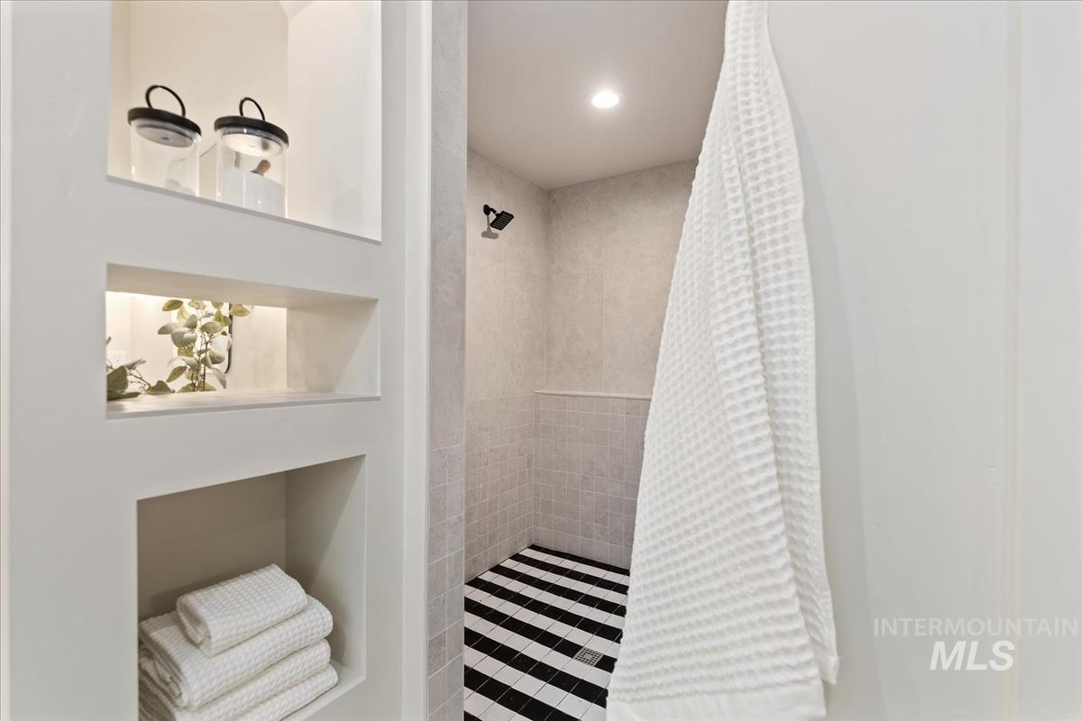 Full bath with tiled shower, recessed lighting, and built in shelves