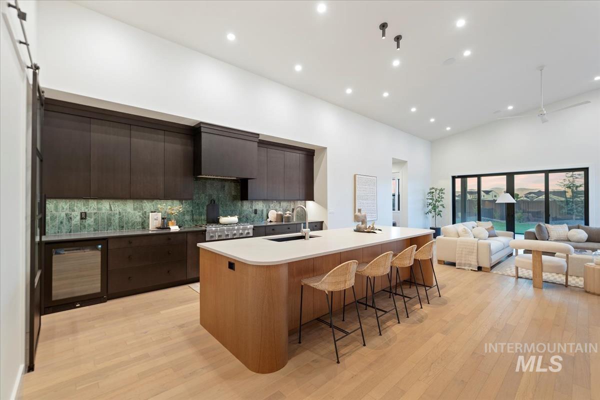 Kitchen featuring modern cabinets, recessed lighting, backsplash, open floor plan, and dark brown cabinets