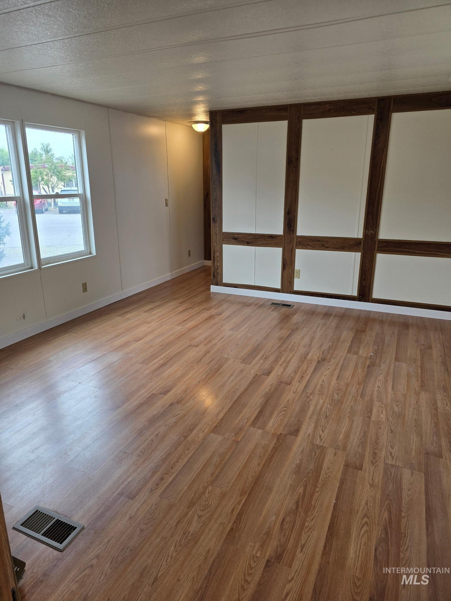Spare room featuring light wood finished floors and a textured ceiling