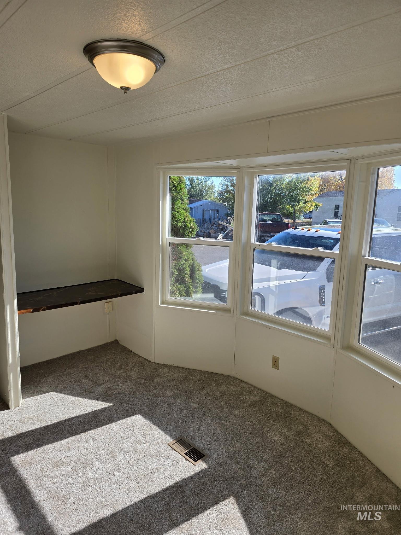 Empty room with carpet flooring and a textured ceiling