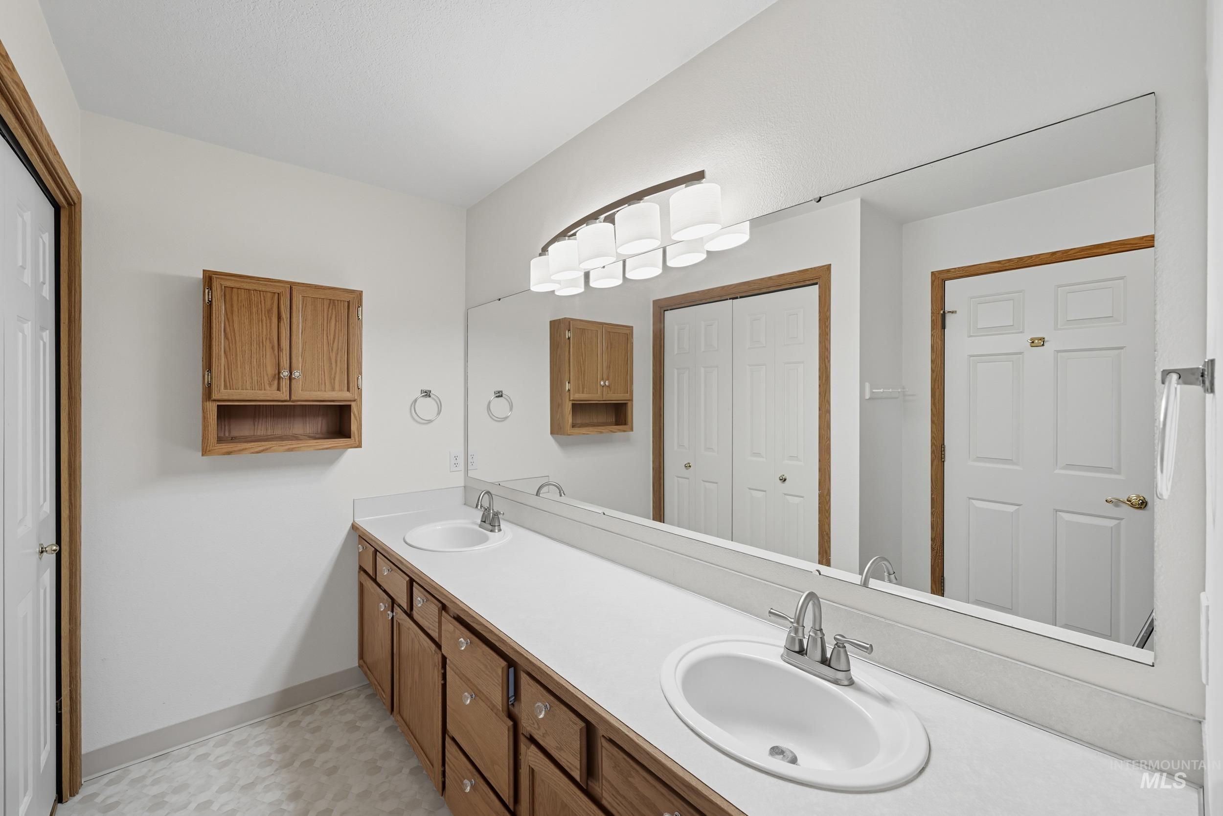 Full bath with double vanity and baseboards