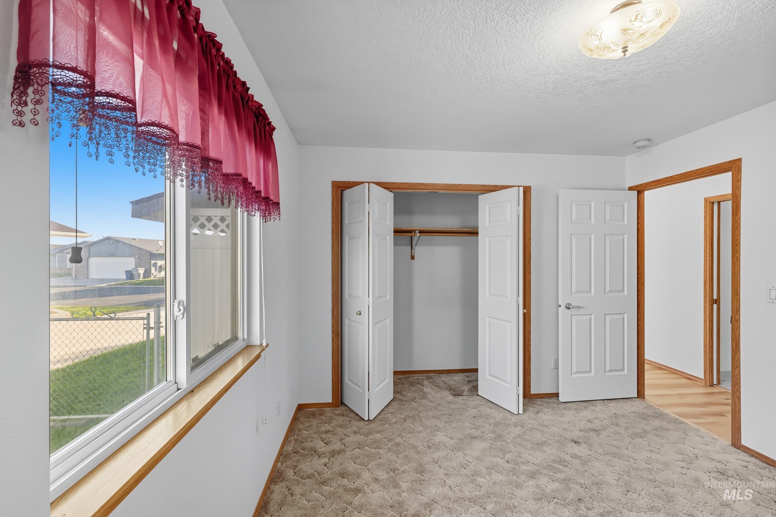 Unfurnished bedroom featuring light colored carpet, a closet, and a textured ceiling