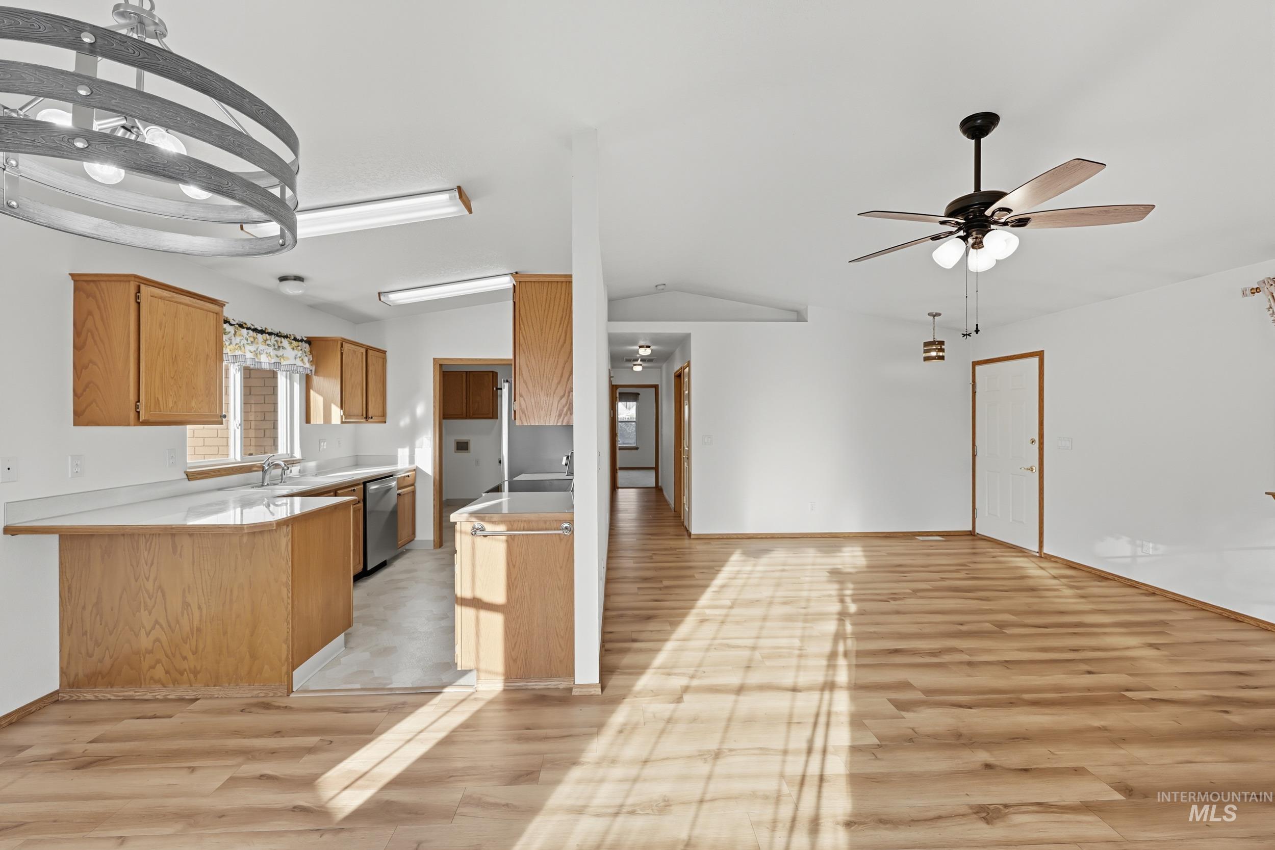 Kitchen with open floor plan, light countertops, lofted ceiling, a peninsula, and a ceiling fan