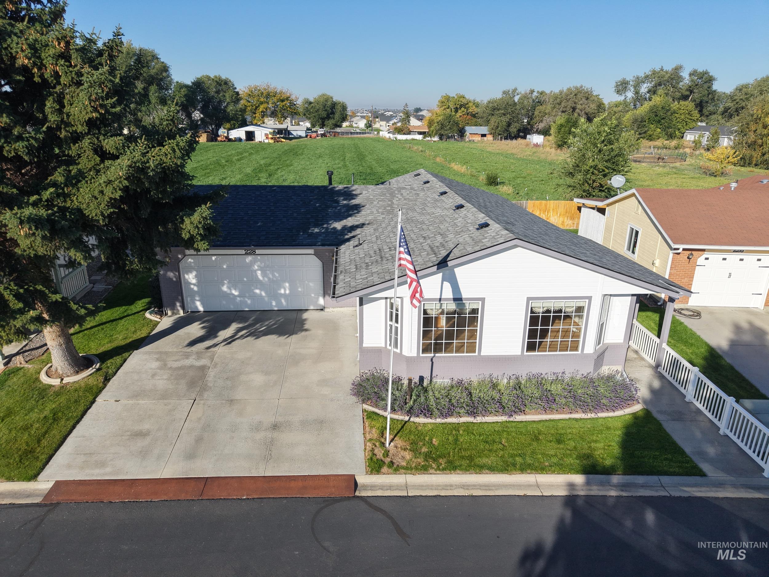 View of front of house featuring driveway, a shingled roof, and a garage