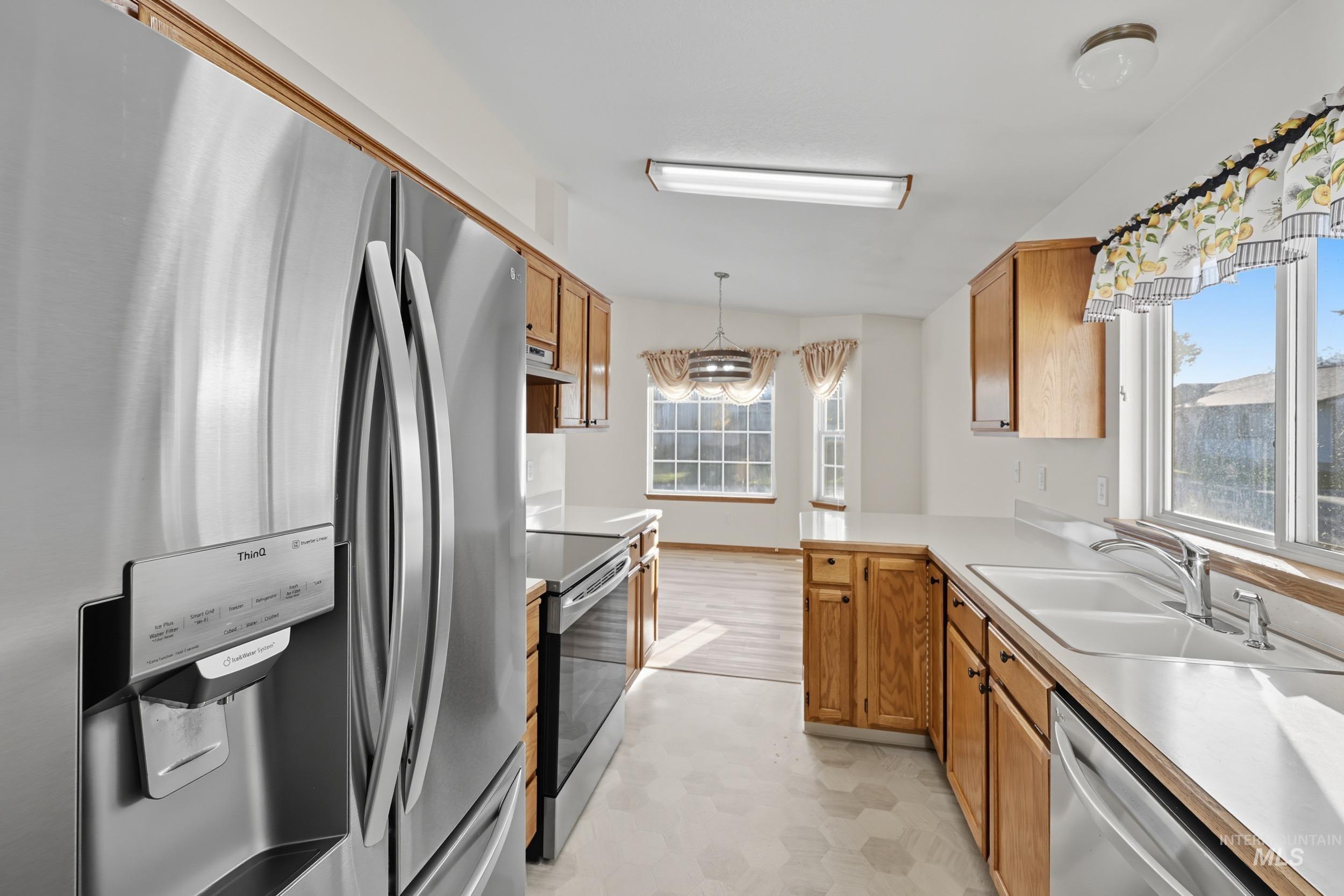Kitchen with appliances with stainless steel finishes, brown cabinets, light countertops, and healthy amount of natural light
