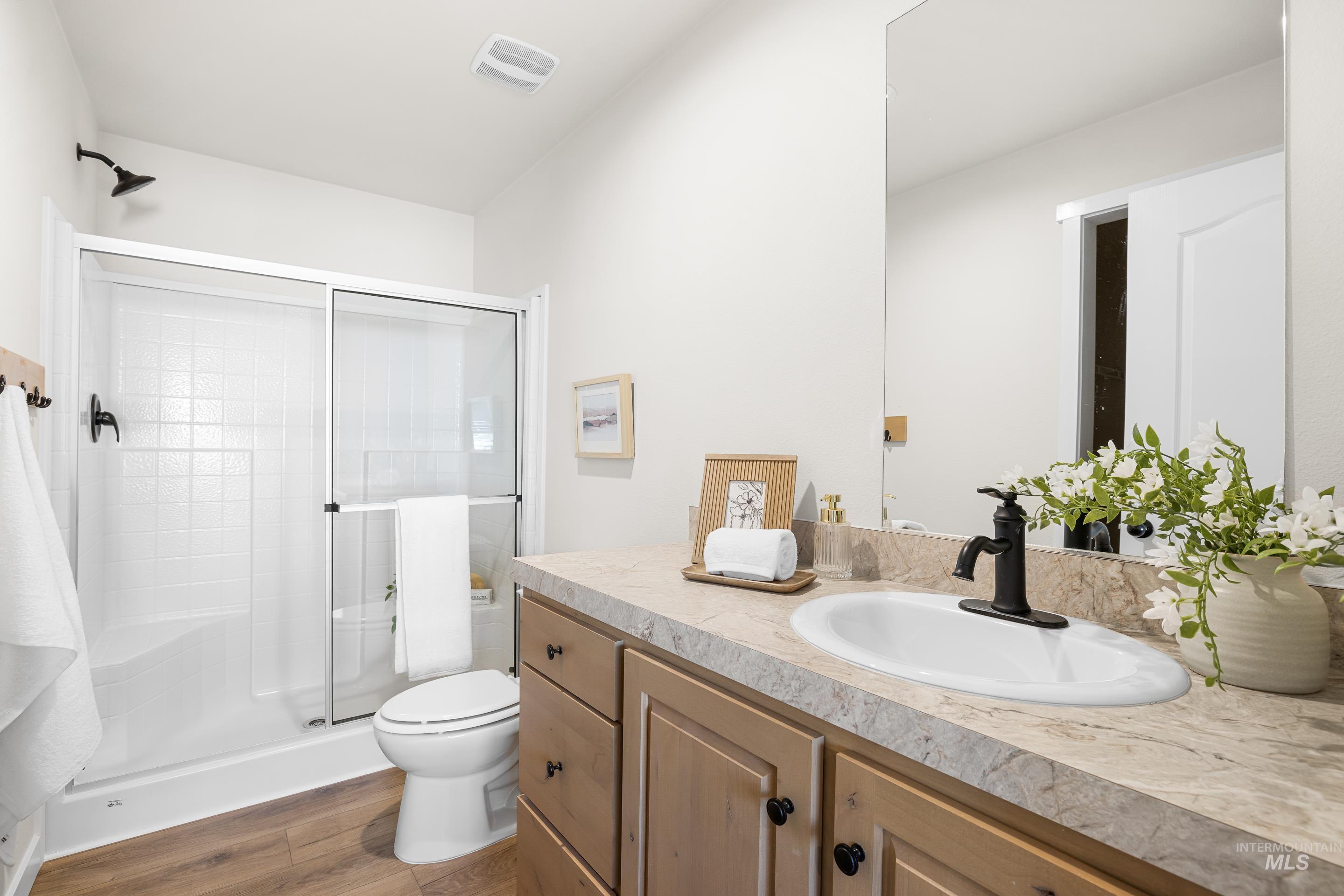 Full bathroom featuring a stall shower, vanity, and dark wood-style floors