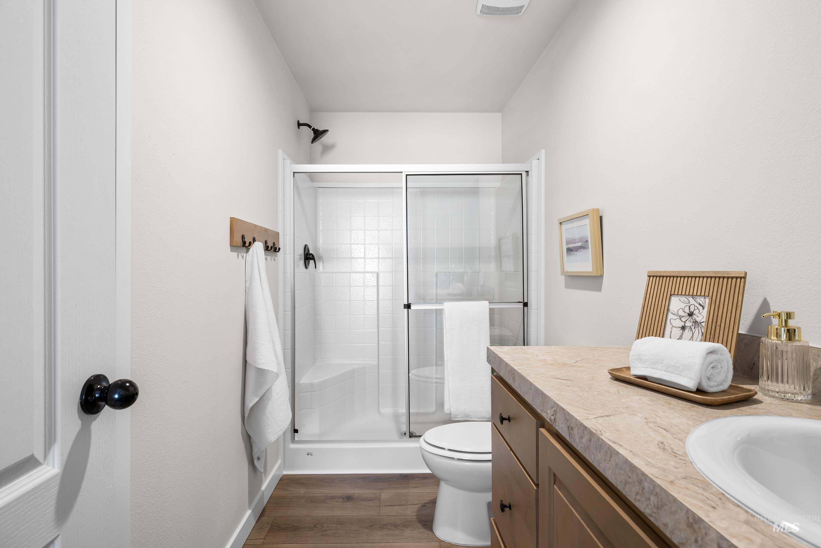 Bathroom with vanity, a shower stall, and dark wood-style flooring