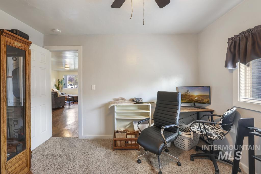 Carpeted office space with a ceiling fan and baseboards