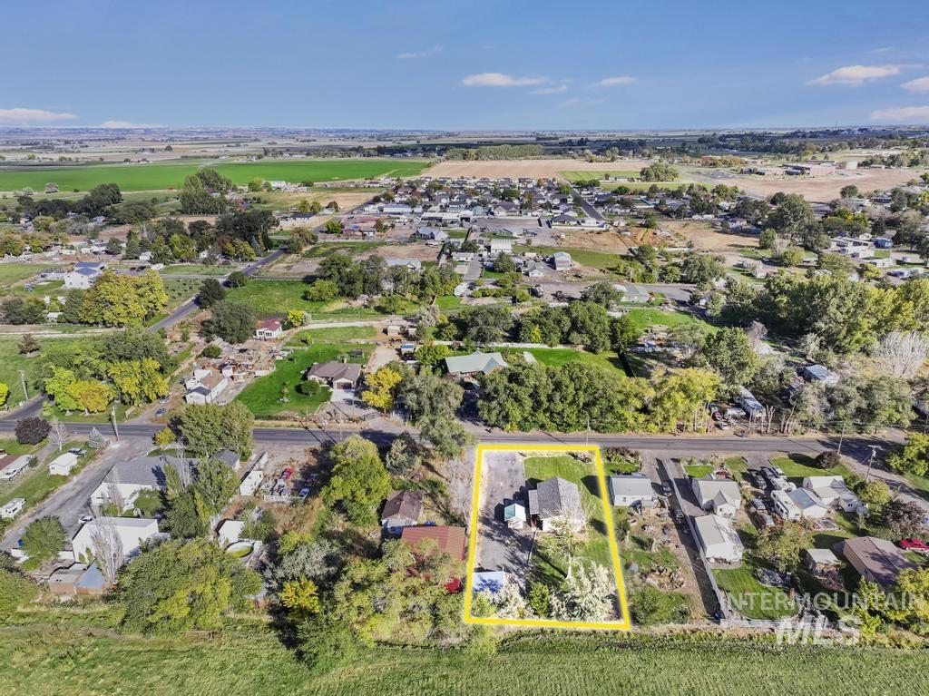 Aerial view of residential area with property parcel outlined and a tree filled landscape