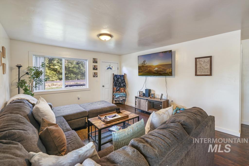 Living area featuring dark wood-type flooring and baseboards