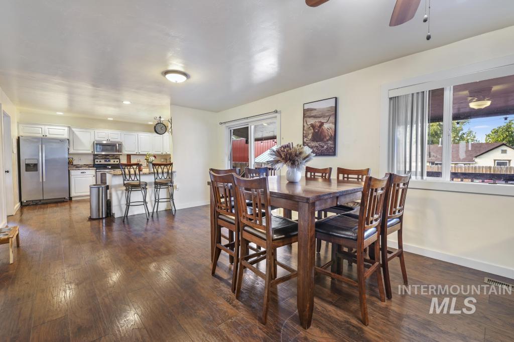 Dining room featuring dark wood finished floors, healthy amount of natural light, and a ceiling fan