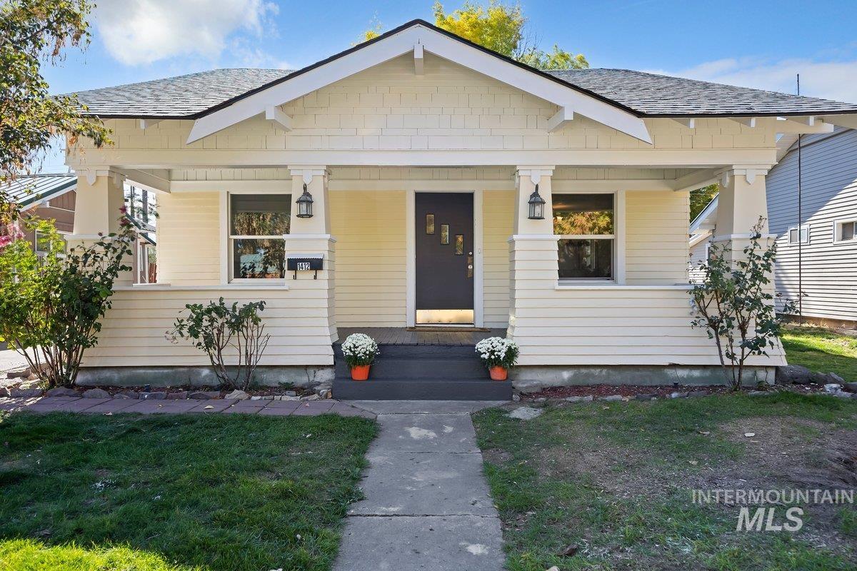 View of front of property with roof with shingles, a porch, and a front lawn