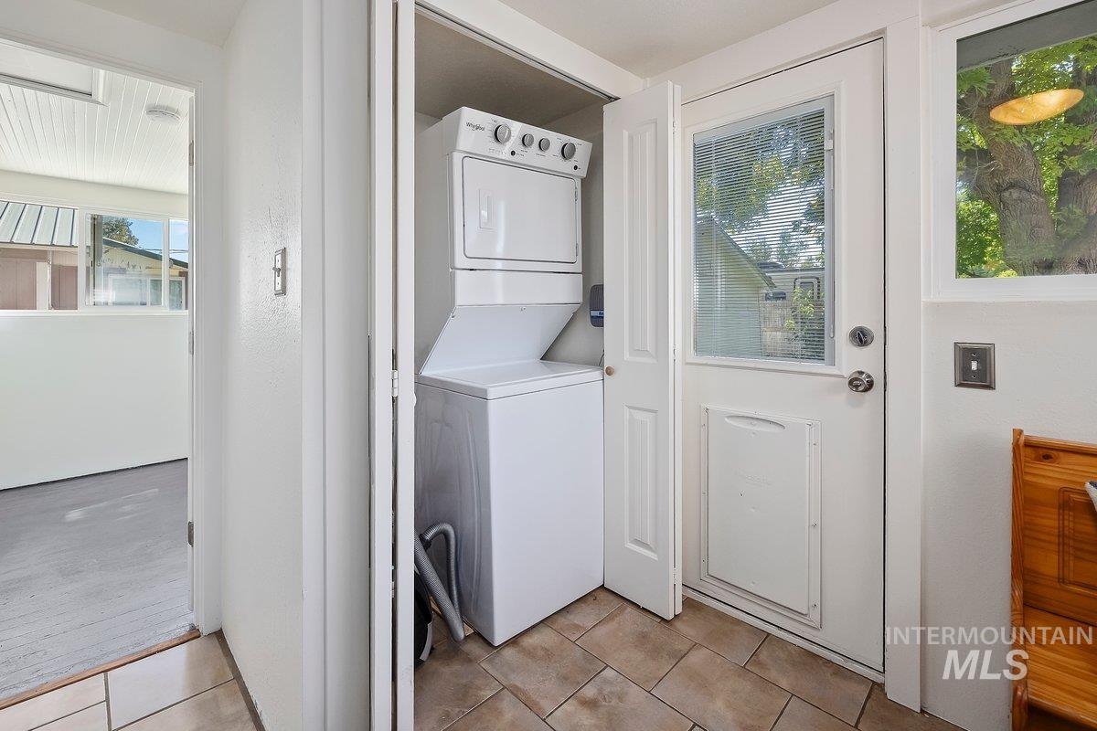 Laundry area with light tile patterned floors and stacked washer and clothes dryer