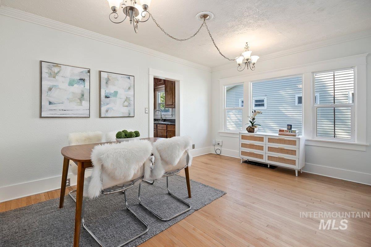 Dining space featuring a chandelier, light wood-style floors, crown molding, and a textured ceiling