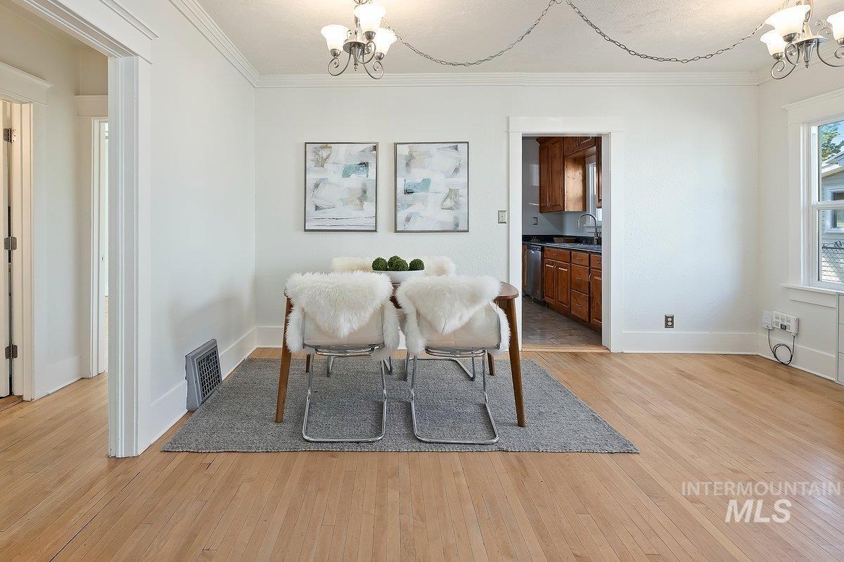 Dining area with a chandelier, light wood-style flooring, and ornamental molding