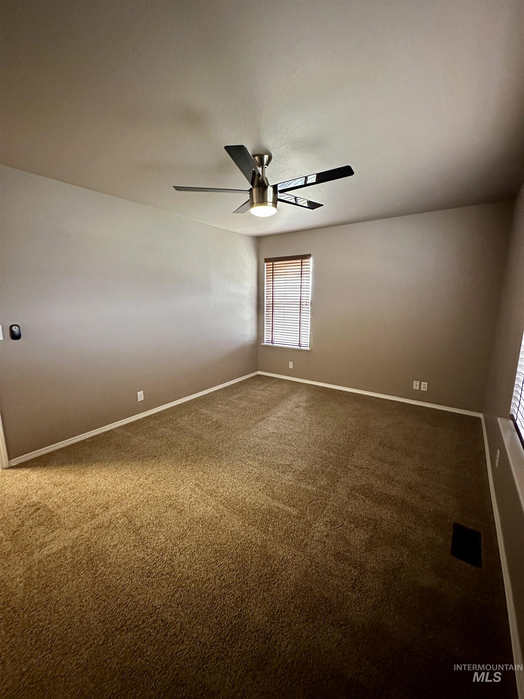 Empty room with dark carpet and ceiling fan