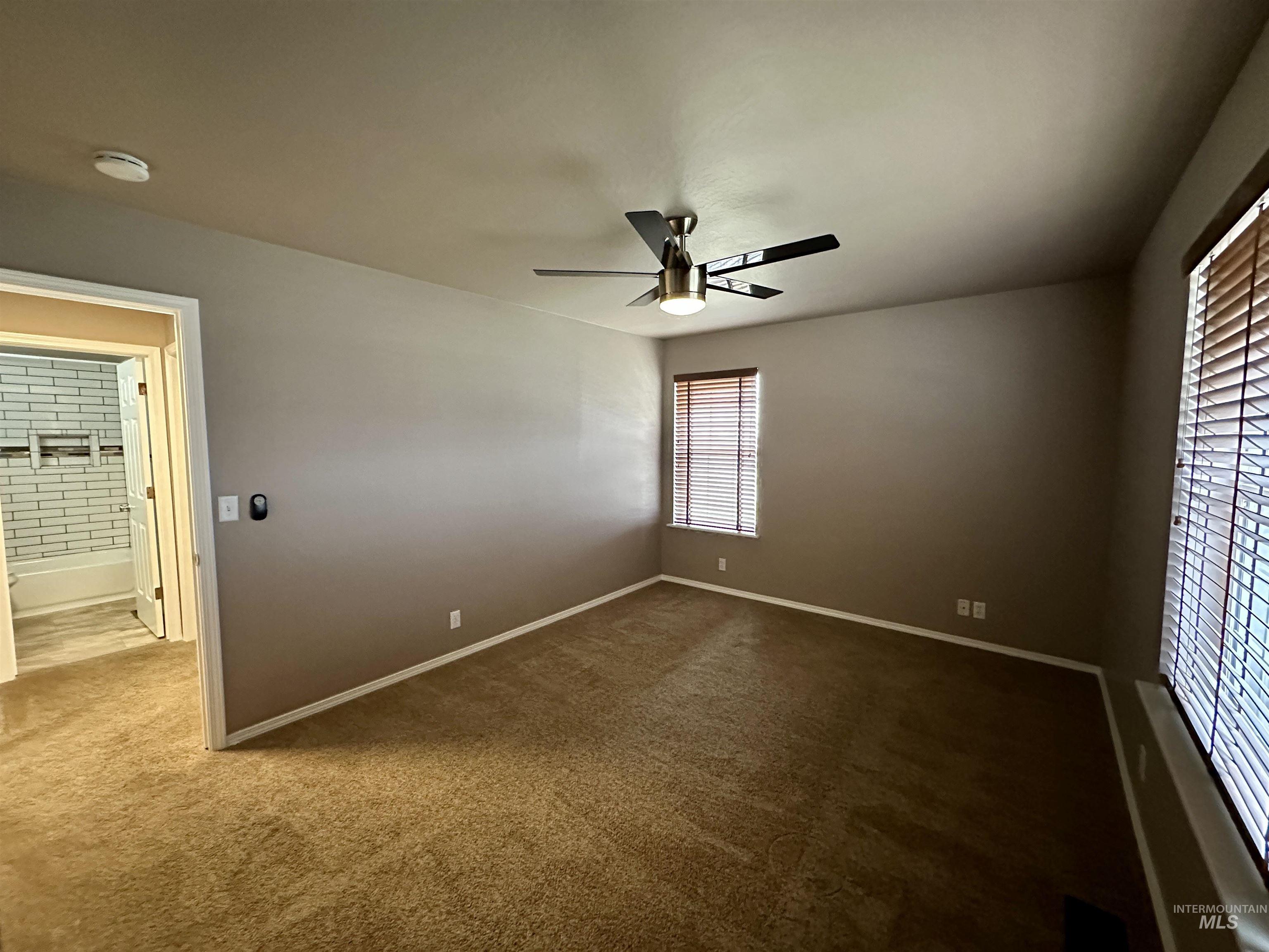 Unfurnished bedroom featuring a ceiling fan and dark colored carpet
