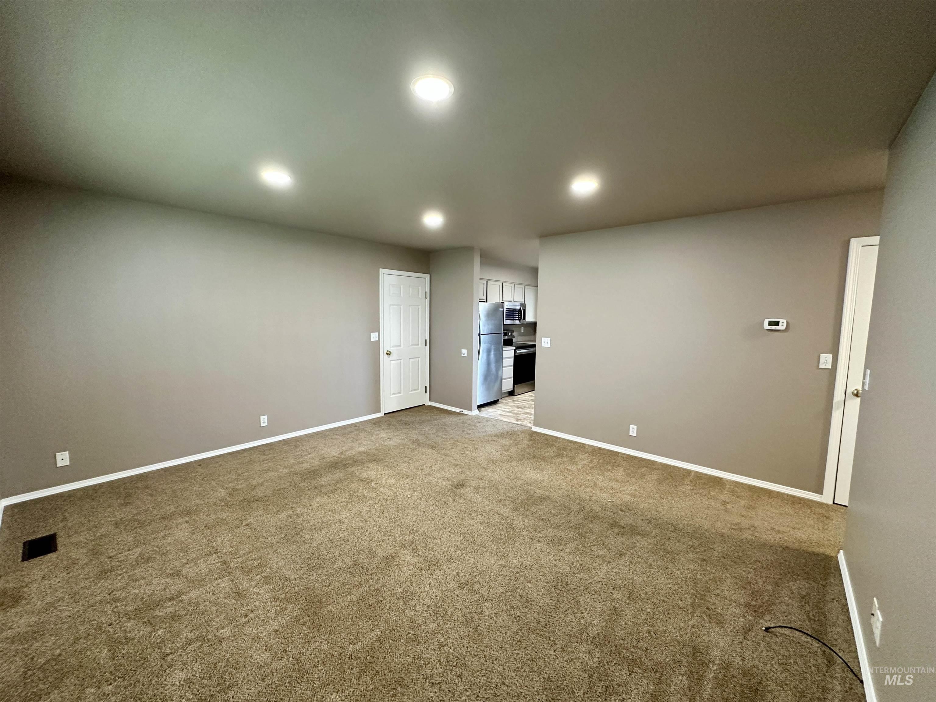 Carpeted empty room featuring baseboards and recessed lighting