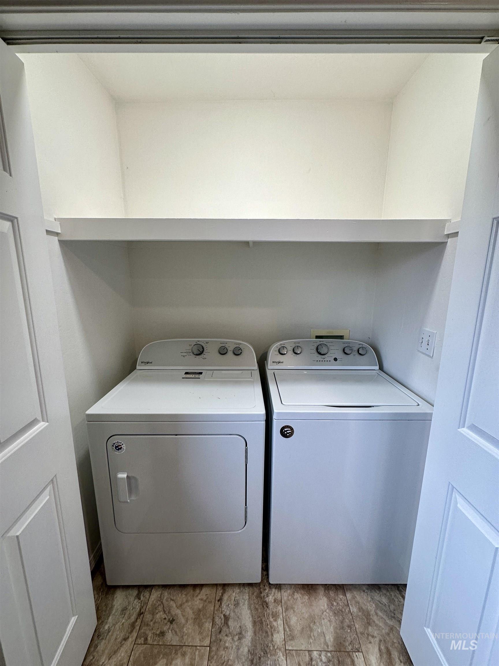 Laundry room with washing machine and dryer and light wood-style floors