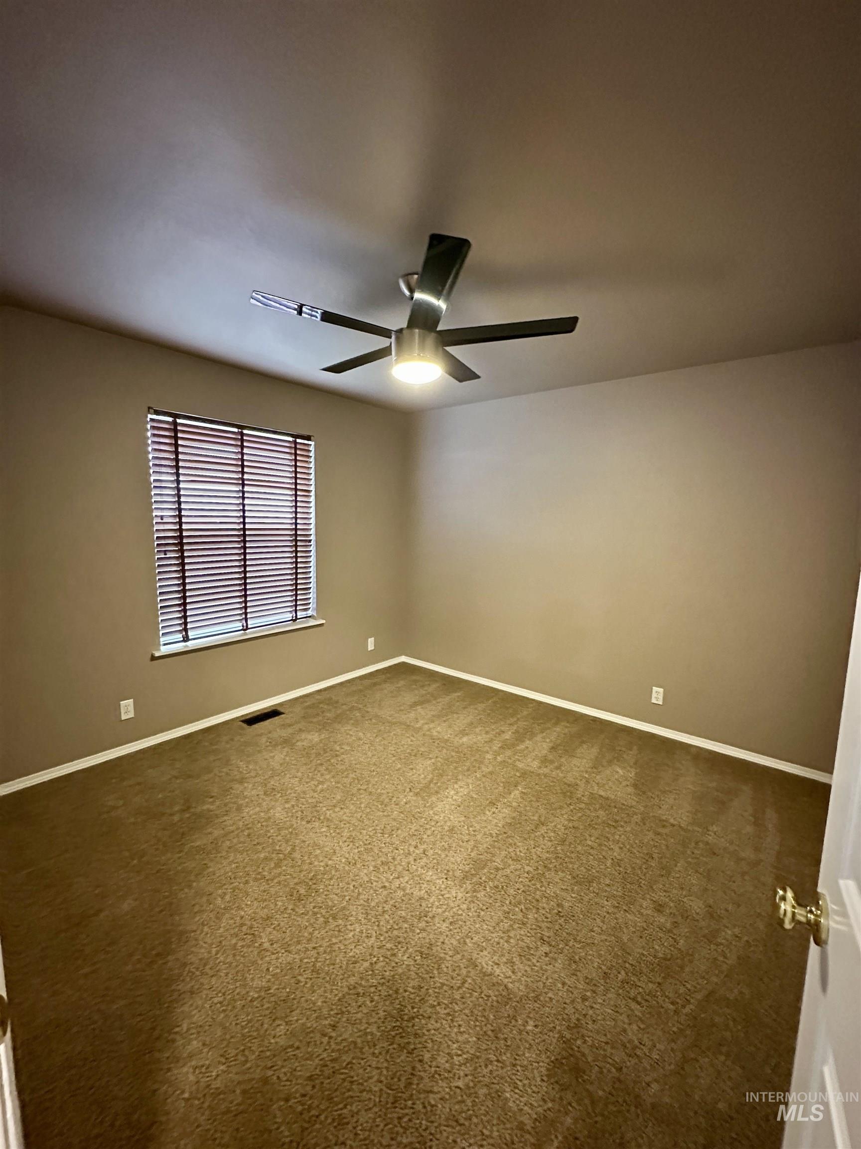 Empty room with carpet flooring and a ceiling fan