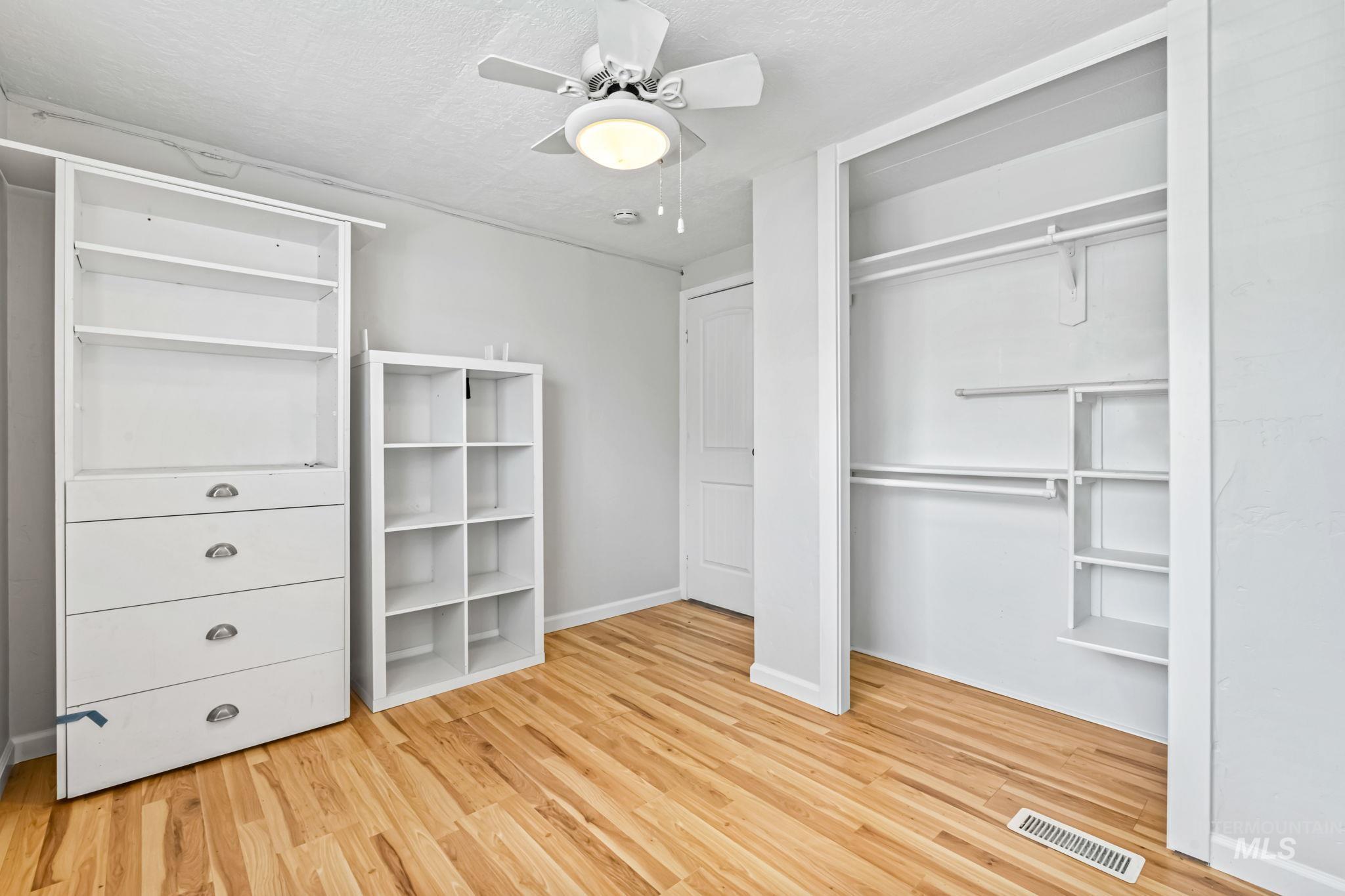 Unfurnished bedroom with light wood finished floors, ceiling fan, a textured ceiling, and a closet