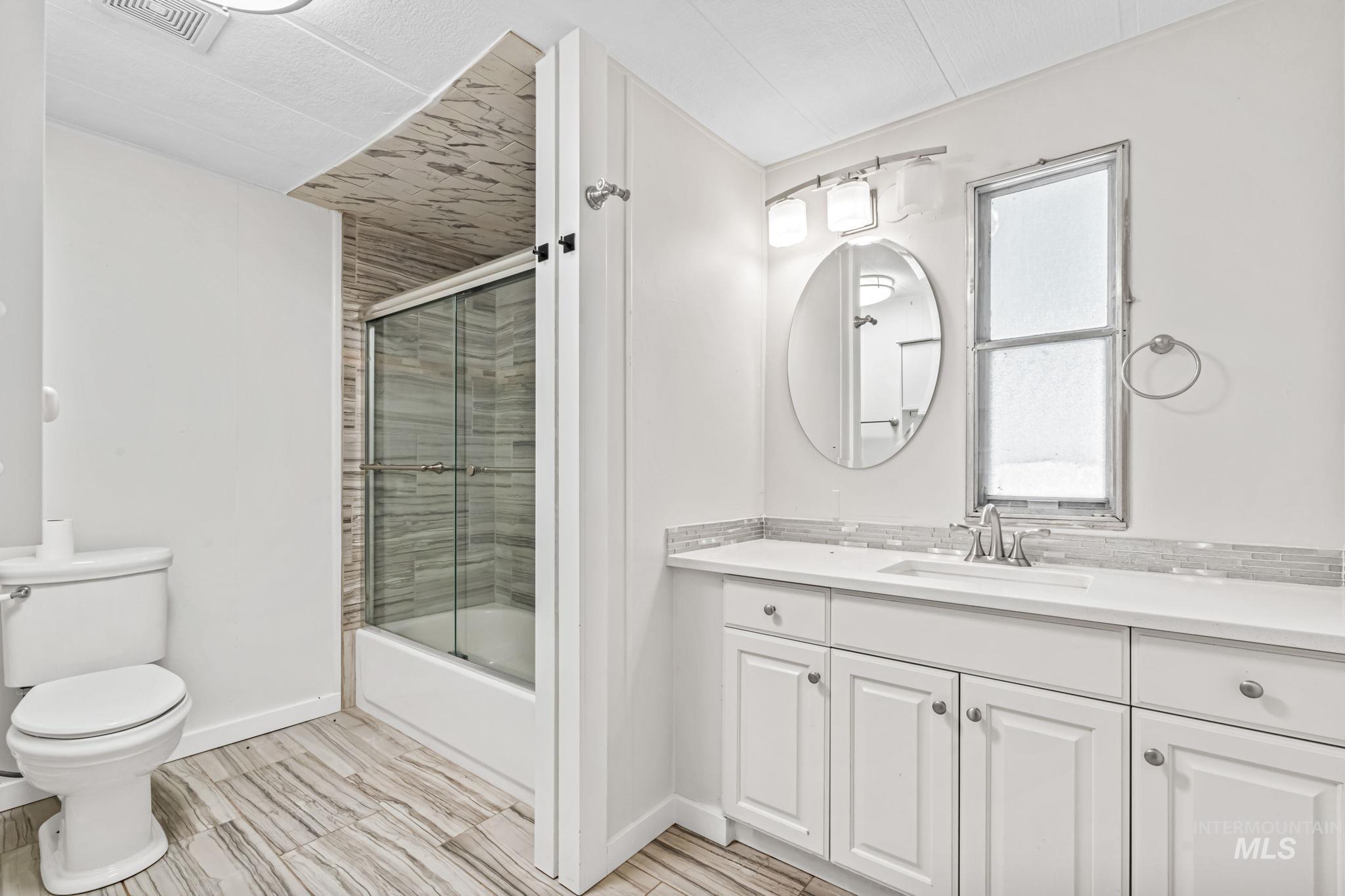 Full bathroom with bath / shower combo with glass door, vanity, and wood finish floors