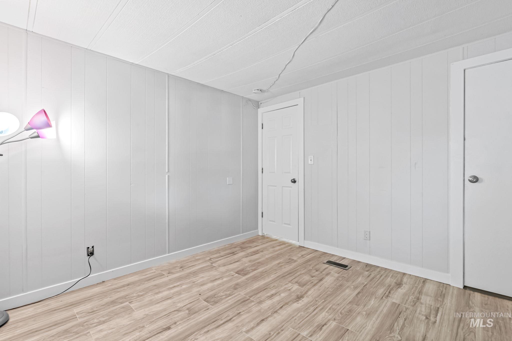 Unfurnished room with light wood finished floors and wood walls