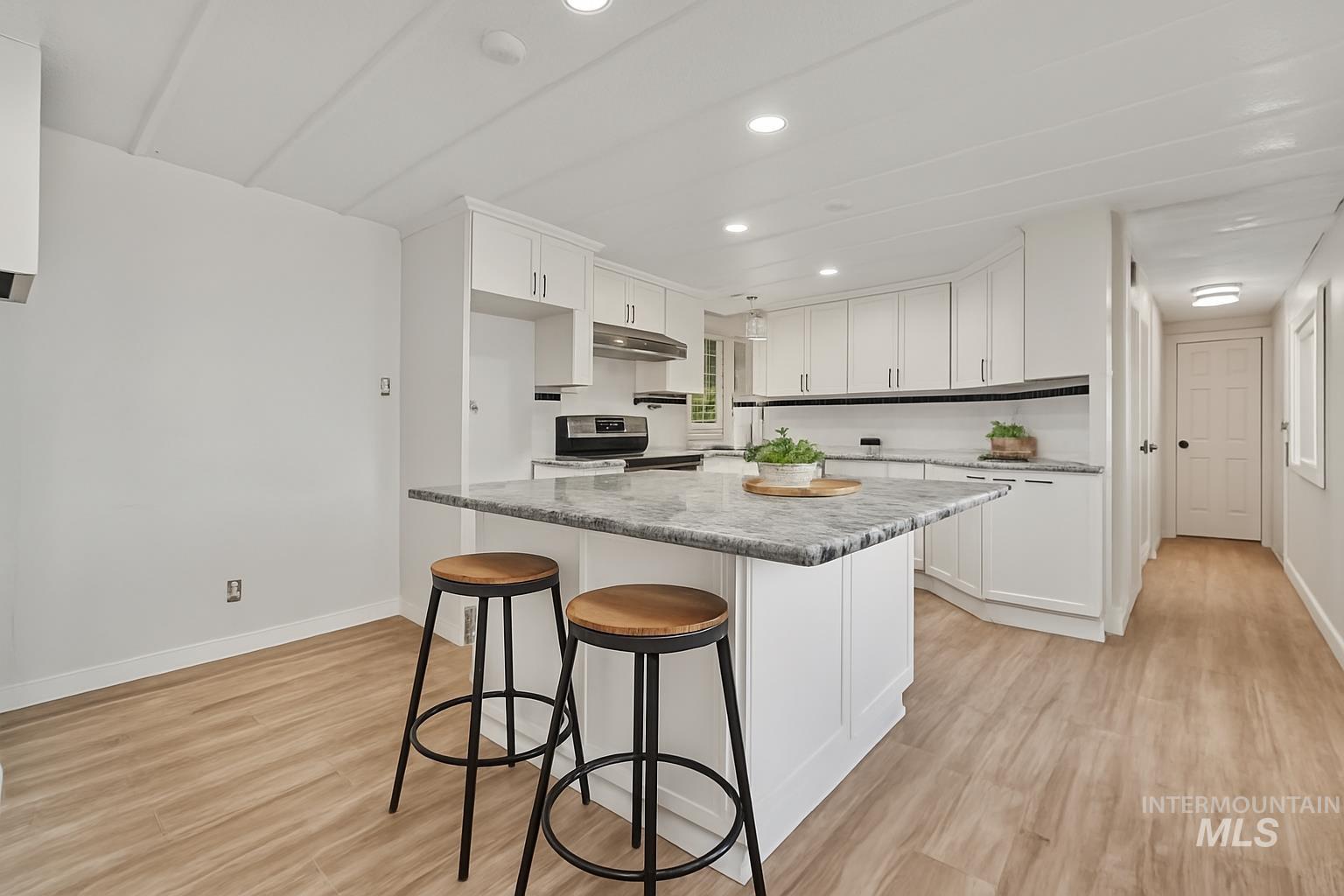 Kitchen with white cabinets, light wood-style flooring, a breakfast bar, recessed lighting, and a center island