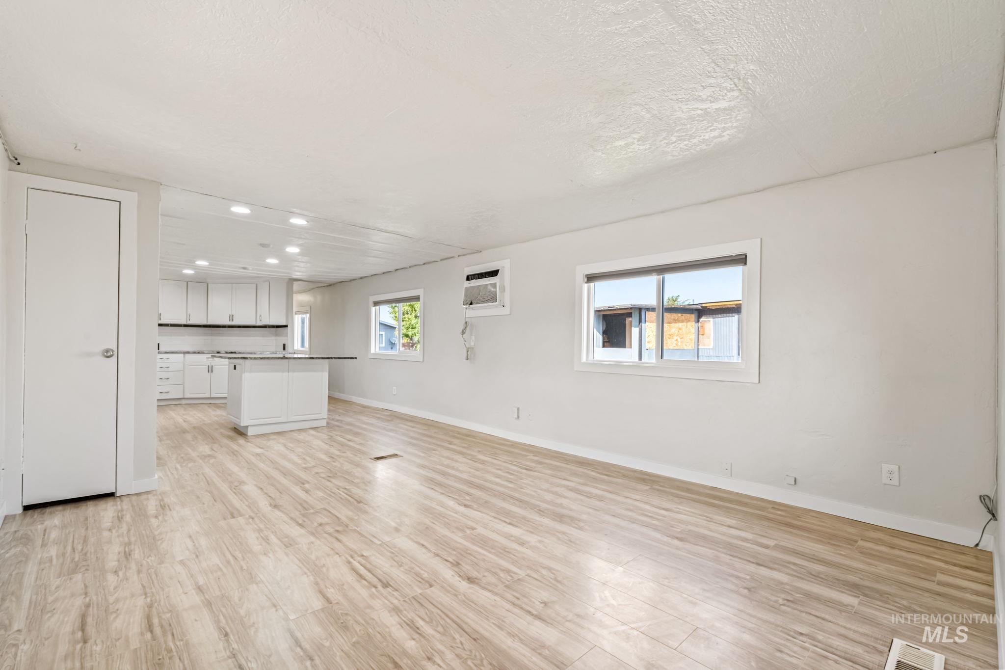 Unfurnished living room with light wood-style flooring, plenty of natural light, recessed lighting, and a wall unit AC