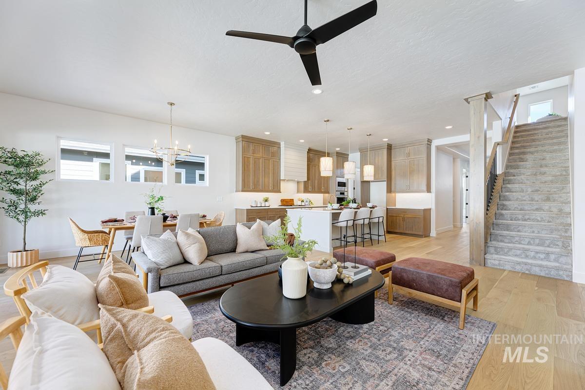 Living room featuring light wood-style floors, stairway, ceiling fan, a chandelier, and recessed lighting