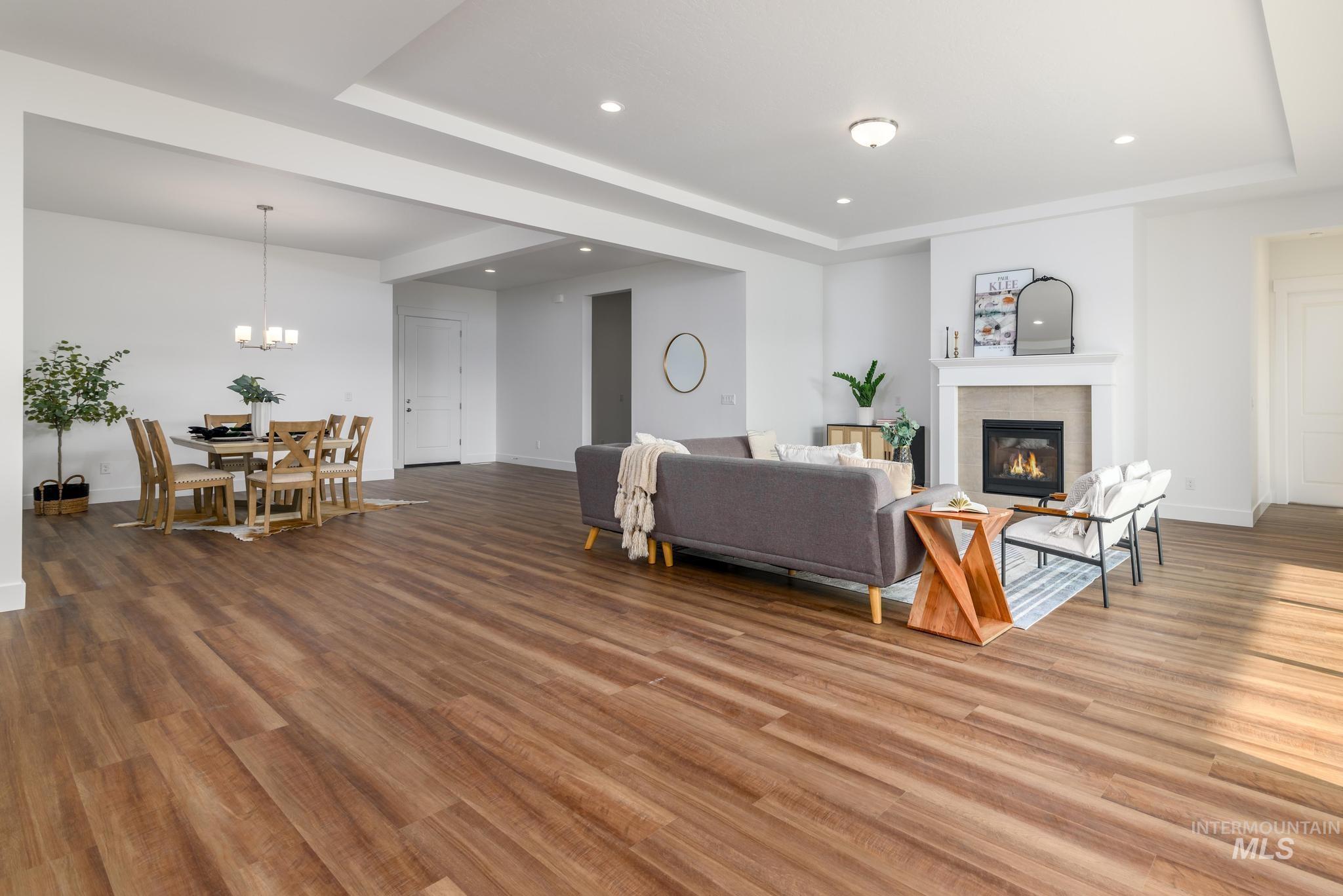 Living room featuring a raised ceiling, recessed lighting, wood finished floors, and a glass covered fireplace