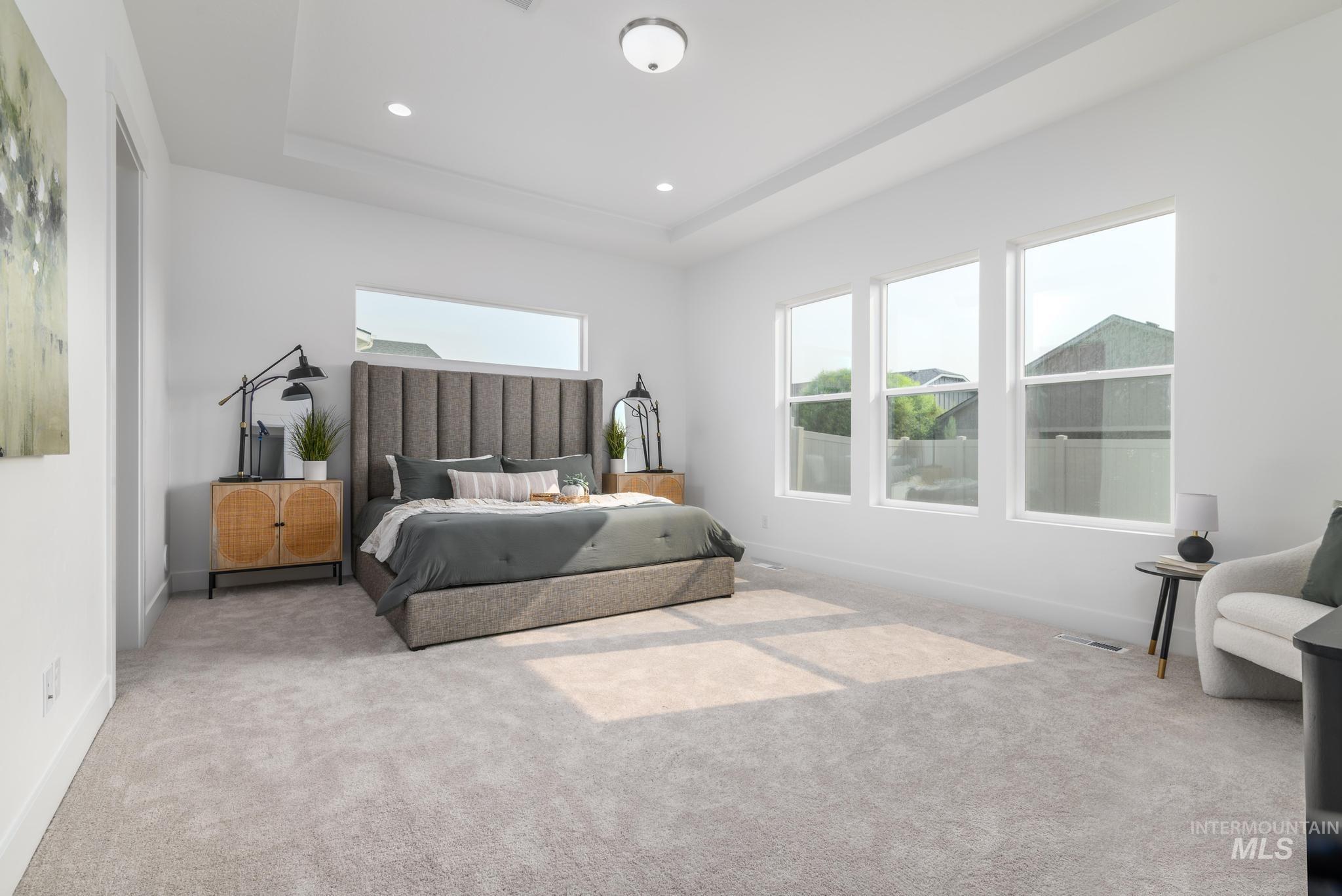 Carpeted bedroom featuring a raised ceiling, multiple windows, and recessed lighting