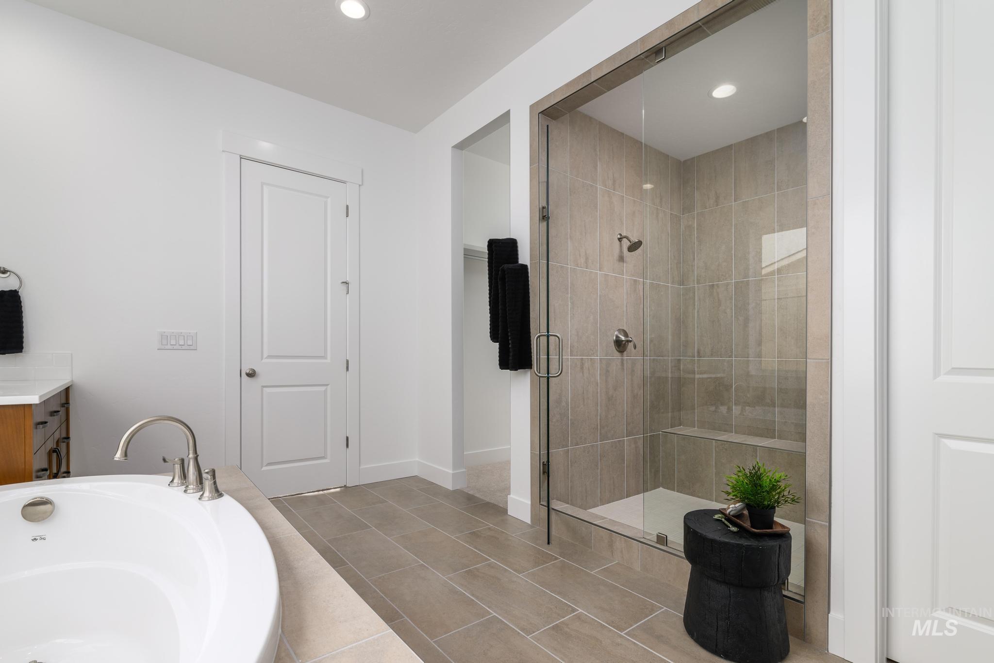Full bath featuring a shower stall, a garden tub, vanity, recessed lighting, and light tile patterned flooring